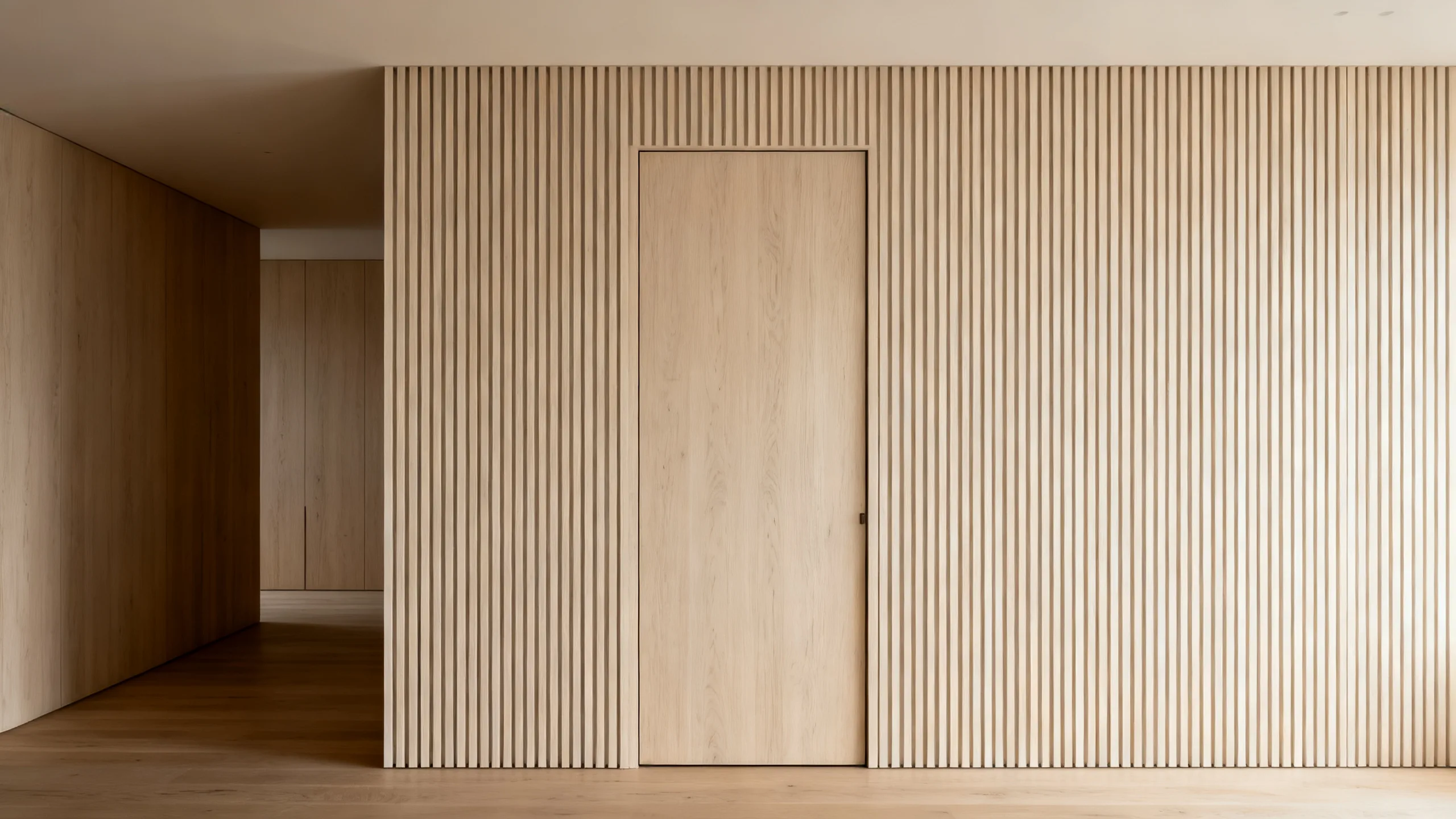 Hidden interior door finished flush with continuous wood-panelled wall in a minimalist luxury suite, no visible frame or architrave